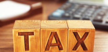 Wooden blocks with word TAX on table, closeup